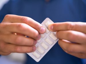 Close-up of two hands gripping a blister-pack of nicotine gum.