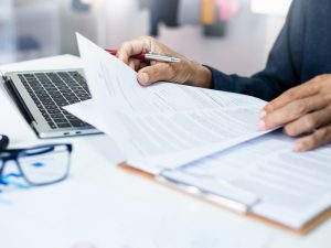 Close-up view of hands holding a document beside a laptop.