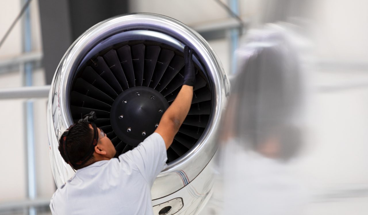 An airplane mechanic checking the jet engine while working on a jet inside the hangar.