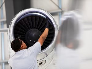 An airplane mechanic checking the jet engine while working on a jet inside the hangar.