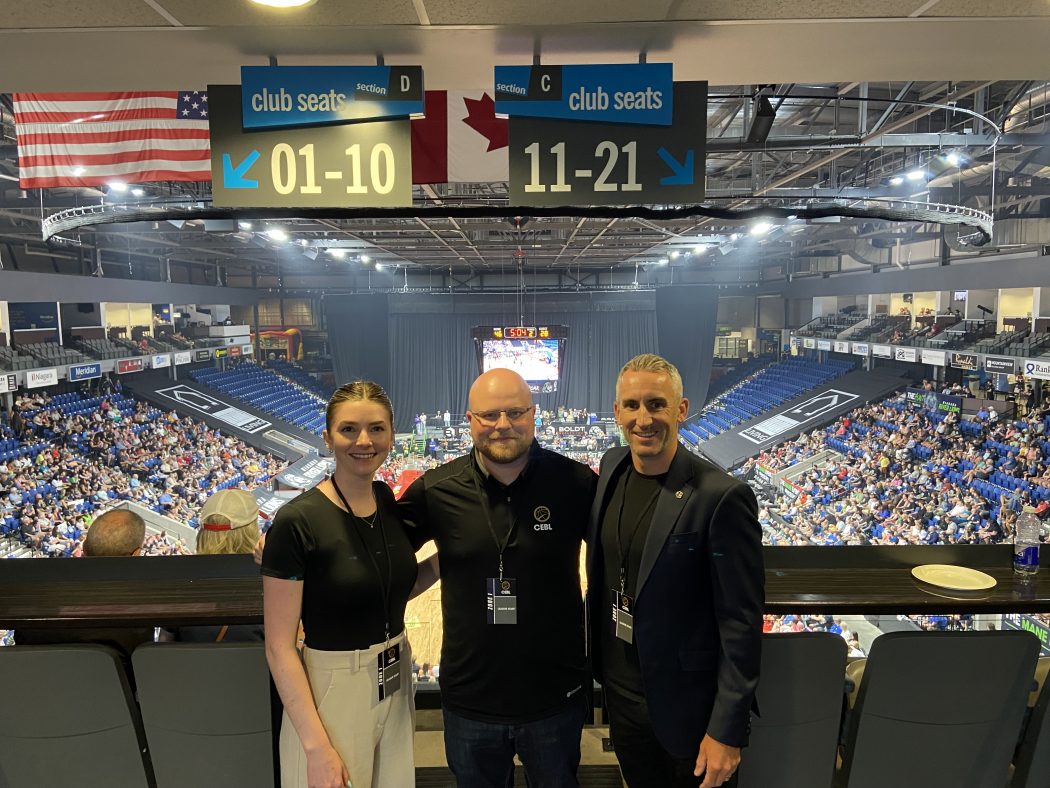 Three people pose for a photo at a basketball game.