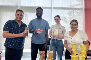 Four people pose for a photo holding packaged foods.