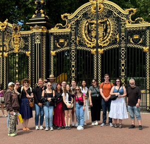 A group of people stand outside in front of the ornate Canada Gate at Buckingham Palace in London, England.