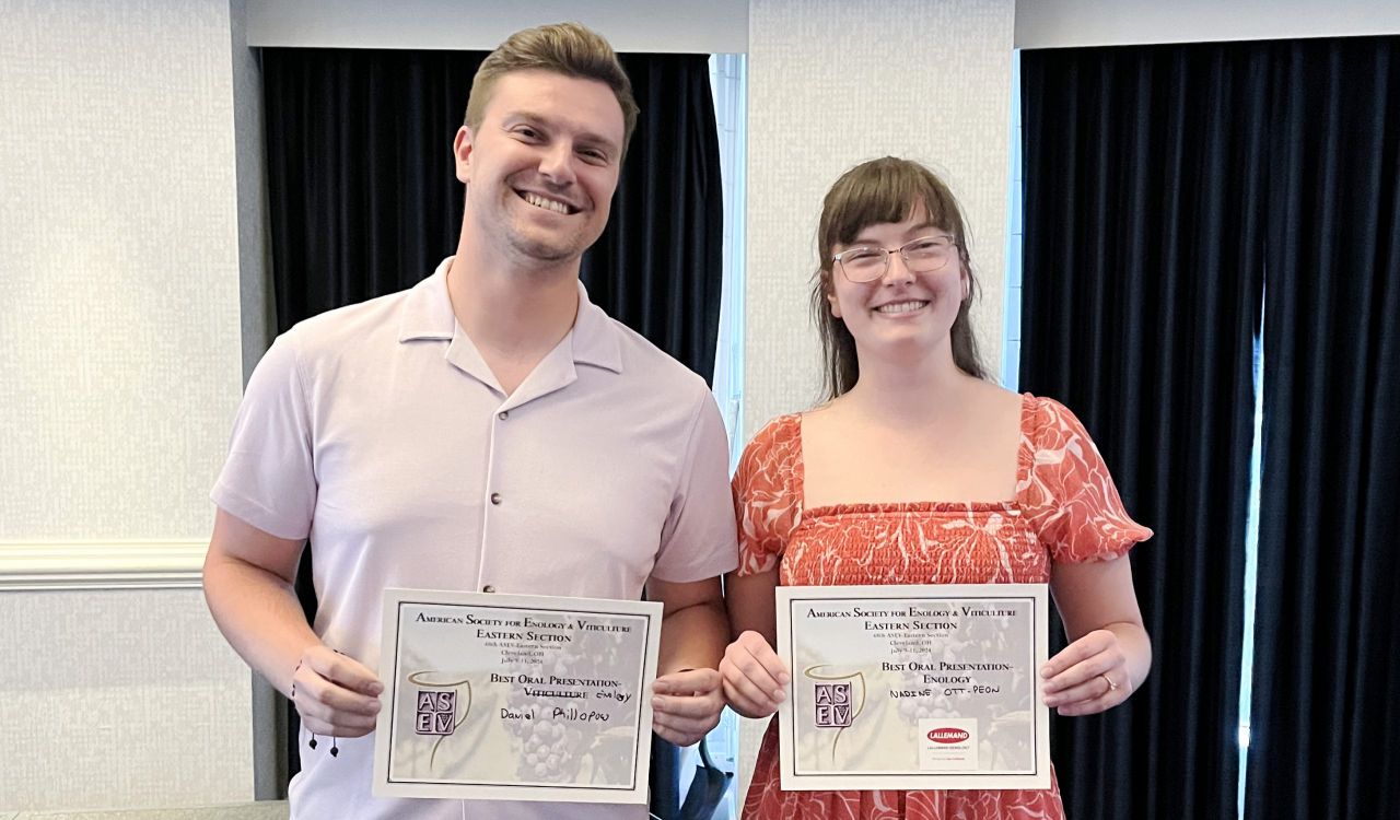 Two people standing next to each other holding first-place certificates.