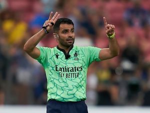 A referee completes a sign with his hands while officiating the sport of rugby outdoors.