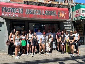 University students pose on the sidewalk under the awning of the Proyecto Justica Laboral (Workers’ Justice Project) in Brooklyn, New York.