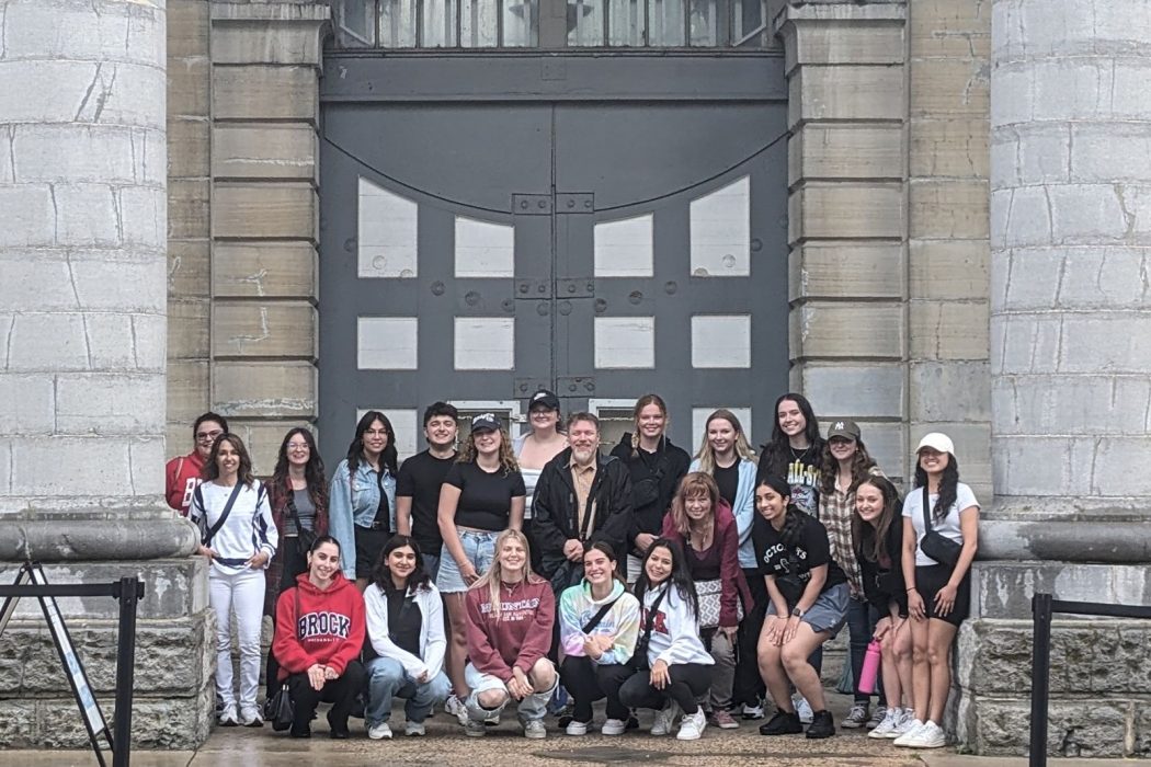 A large group of people pose for a photo on the steps of a historic building.