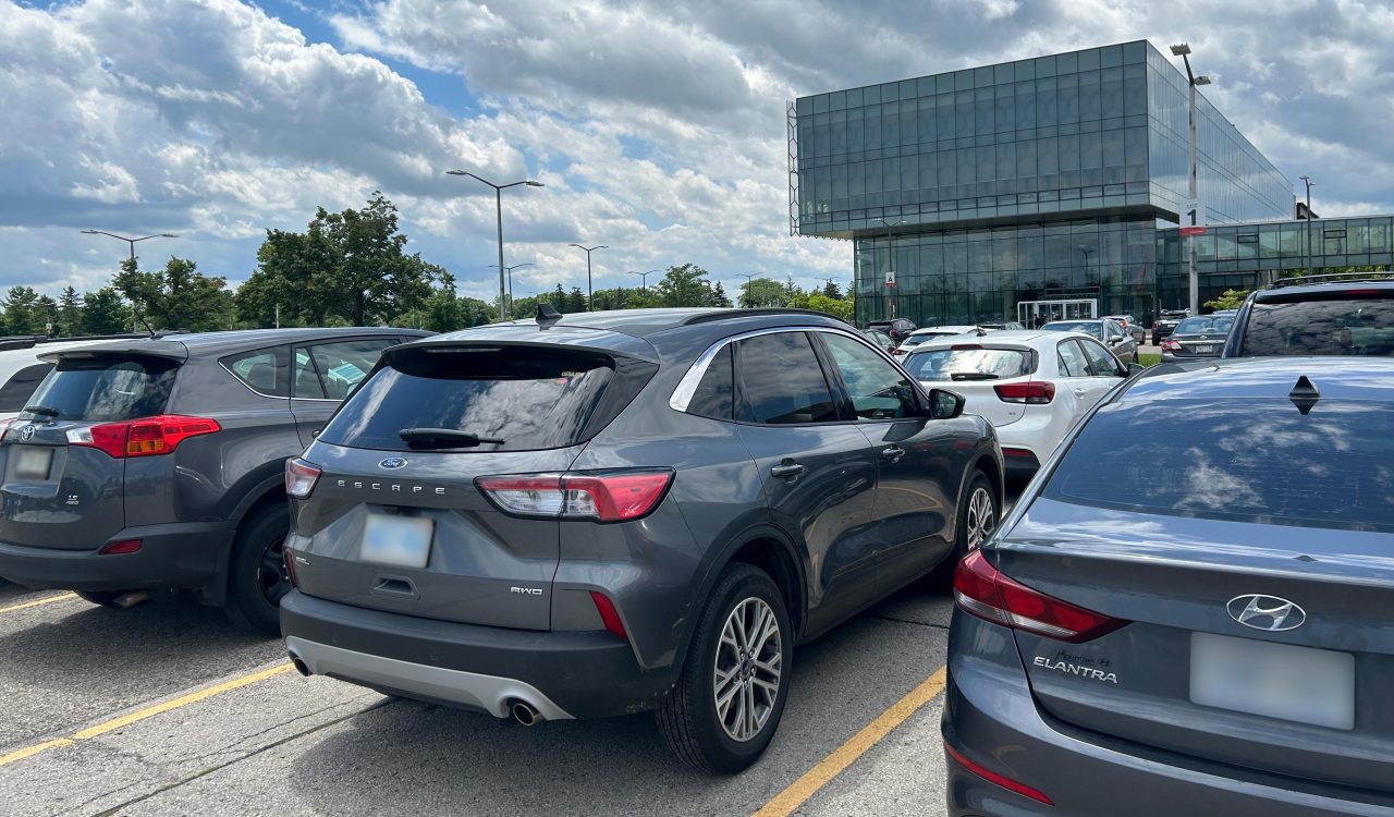 Cars parked in front of a glass building at Brock University.