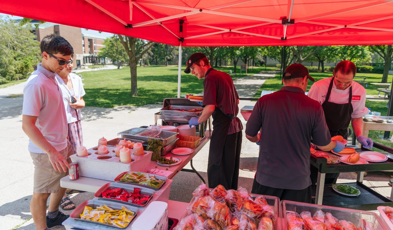 Dining Services staff serve hamburgers and hot dogs from a tent in Jubilee Court.