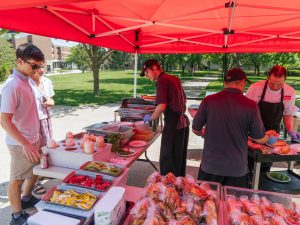 Dining Services staff serve hamburgers and hot dogs from a tent in Jubilee Court.