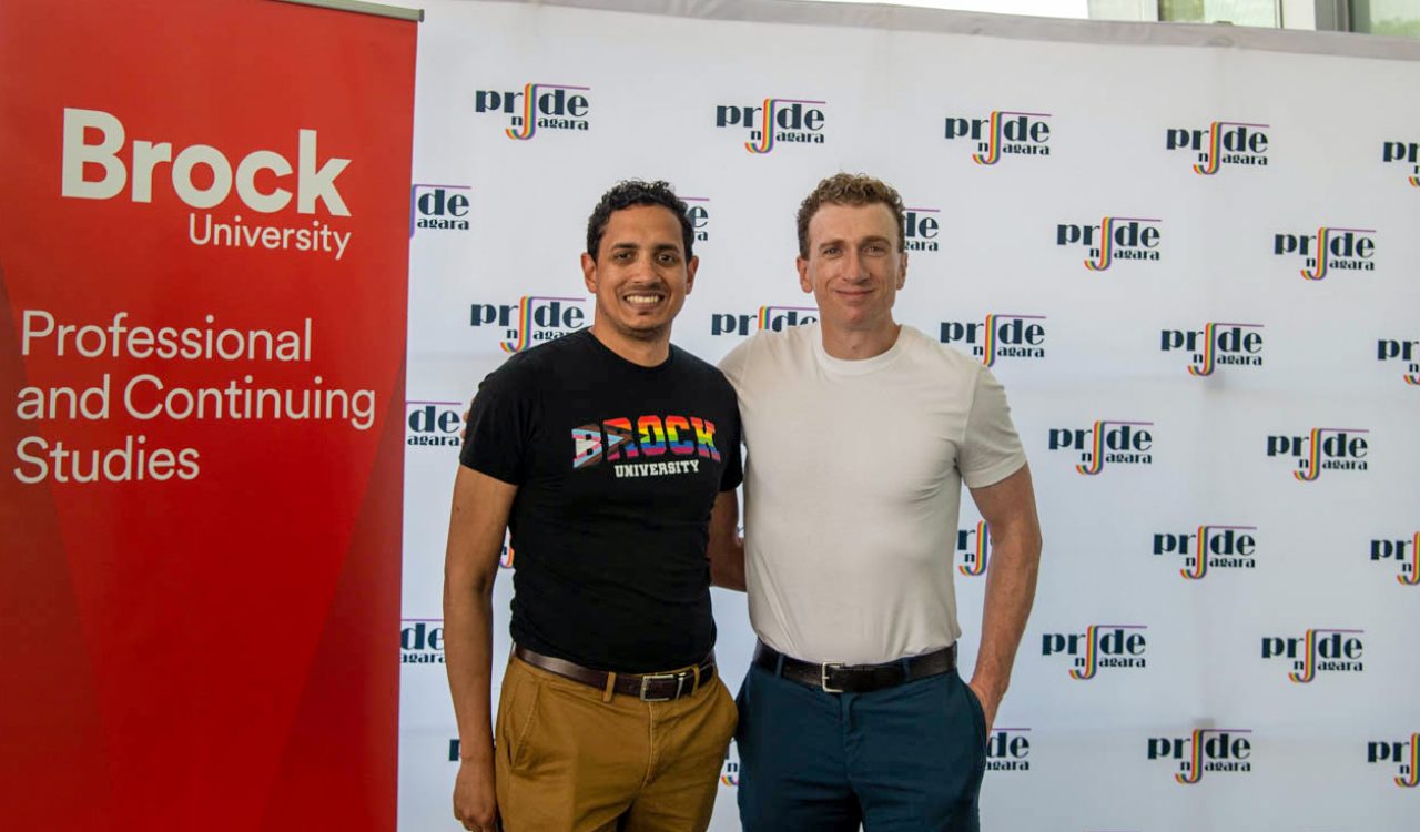 Two men pose in front of pull-up banners.