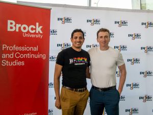 Two men pose in front of pull-up banners.