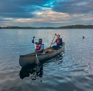 Two people paddle a canoe on a lake.