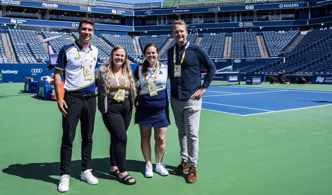 Four people stand together on the tennis court at Sobeys Stadium in Toronto.