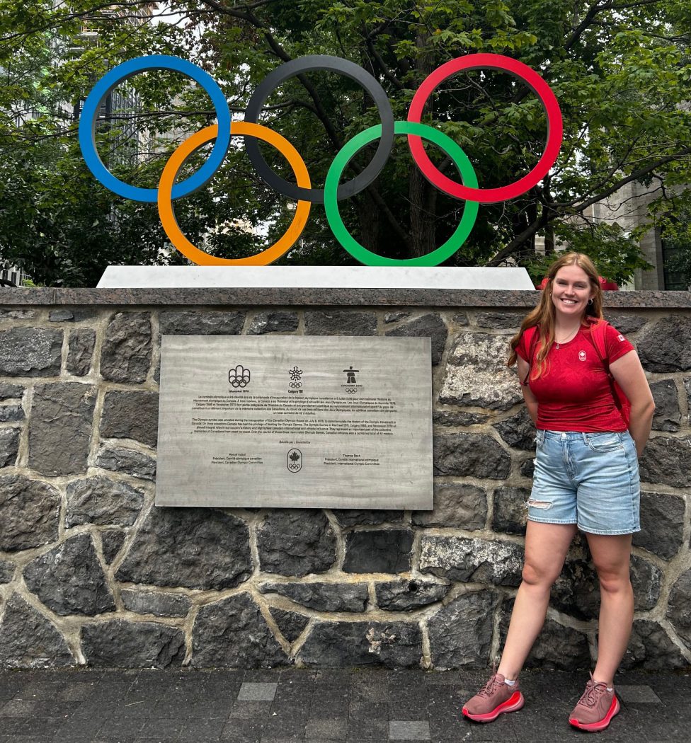 Brynn Booker stands next to the Olympic rings outside in Montréal.