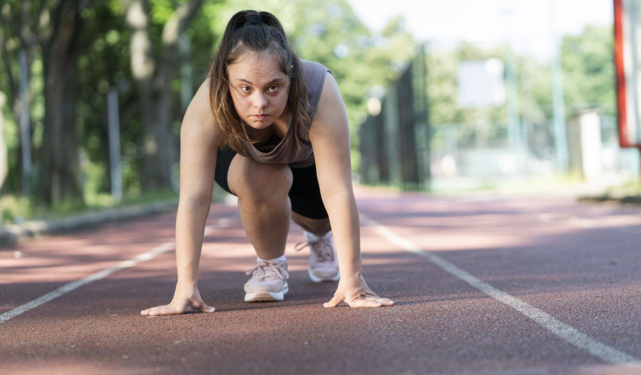 A young woman with Down syndrome prepares to run on an outdoor track.