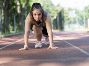 A young woman with Down syndrome prepares to run on an outdoor track.