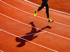 The legs and feet of a woman are seen running on a track.