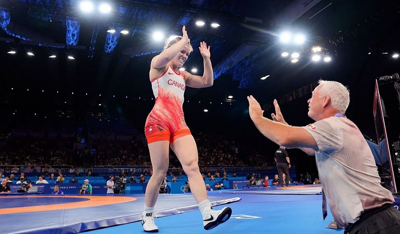 A woman high fives a man while walking off of a wrestling mat in Paris, France.