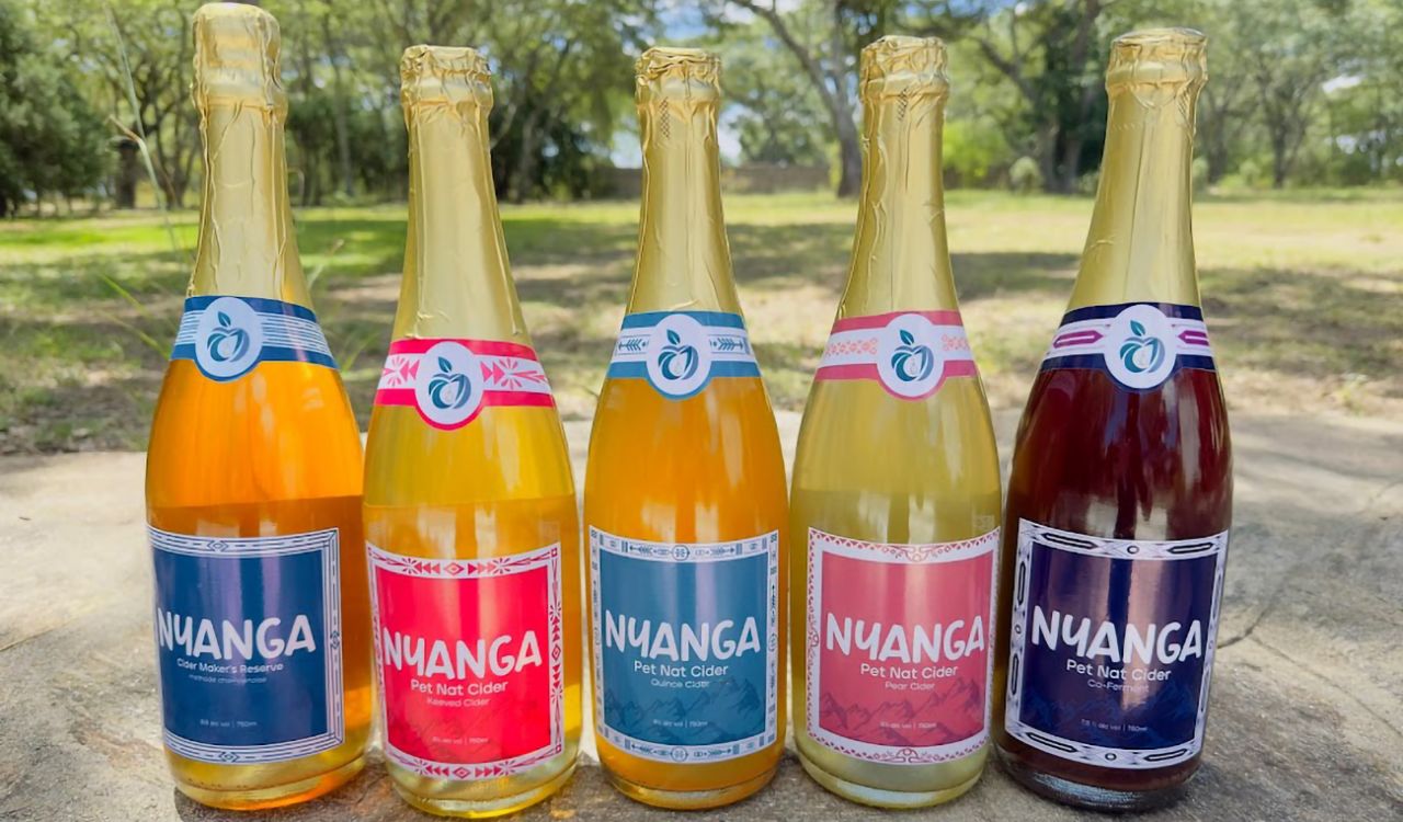 Image of several bottles of cider sitting in the grass.