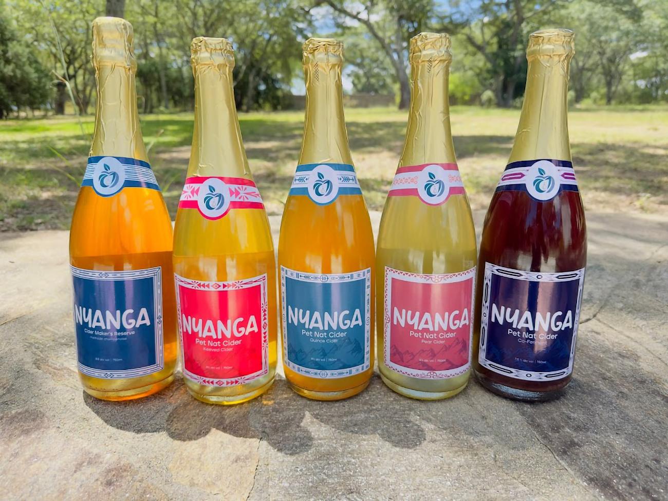 Image of several bottles of cider sitting in the grass.