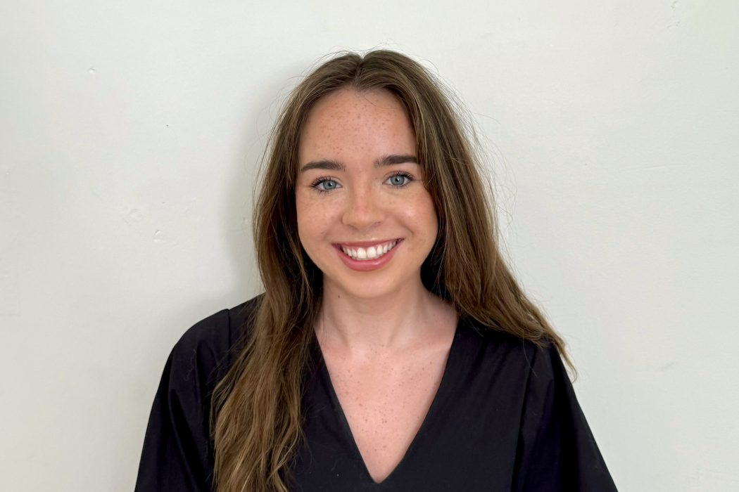 Headshot of a young woman standing in front of a wall.