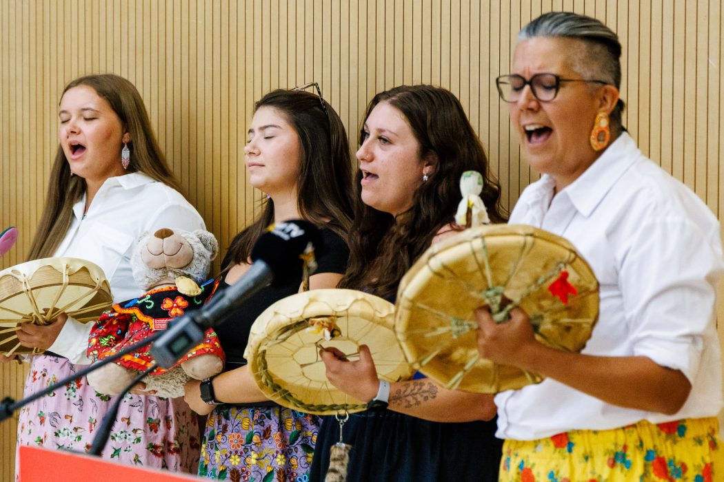 Four women sing with drums in their hands.