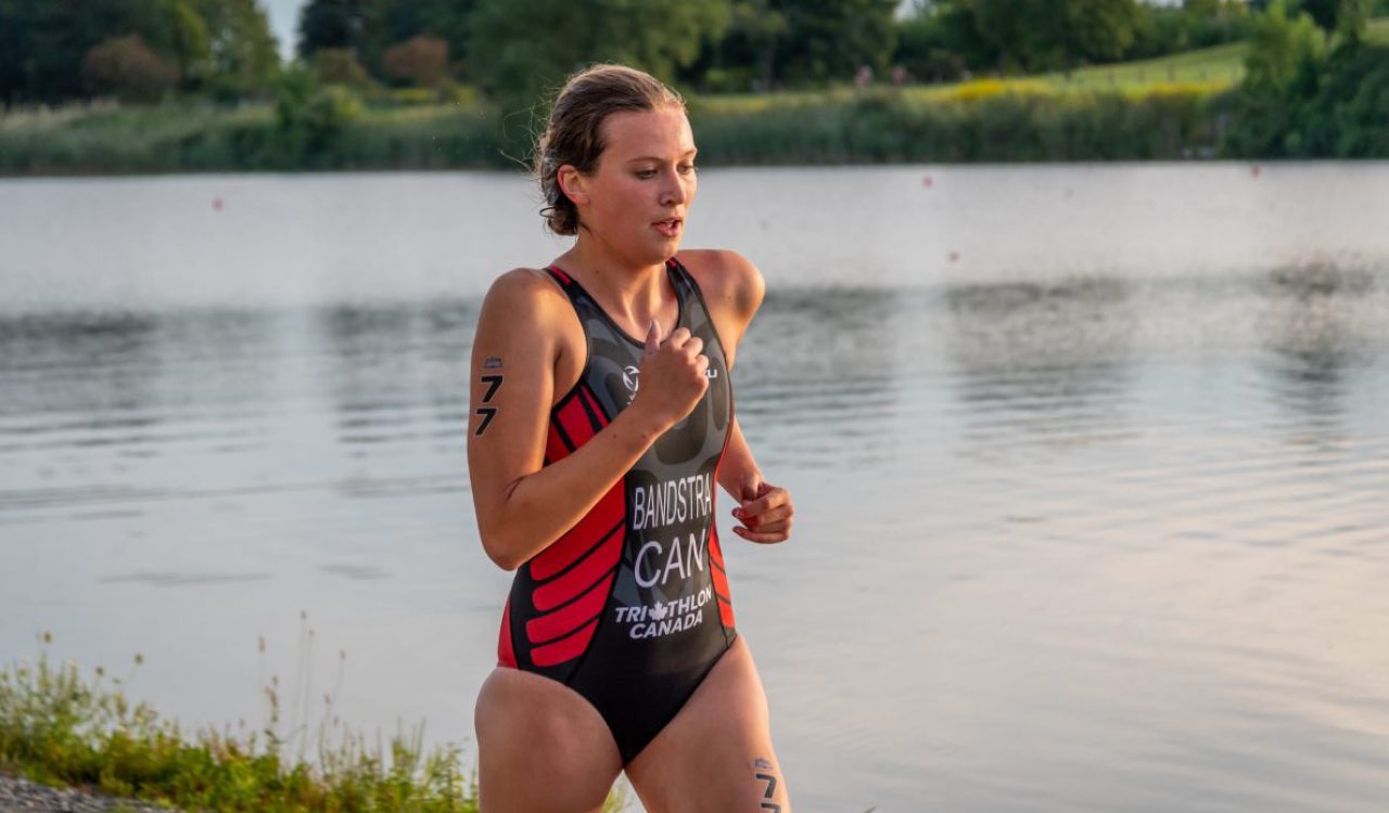 A female athlete runs outdoors while wearing a swimsuit.