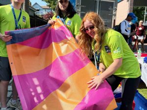 Three students hold a colourful banner they have removed and folded to be stored away.