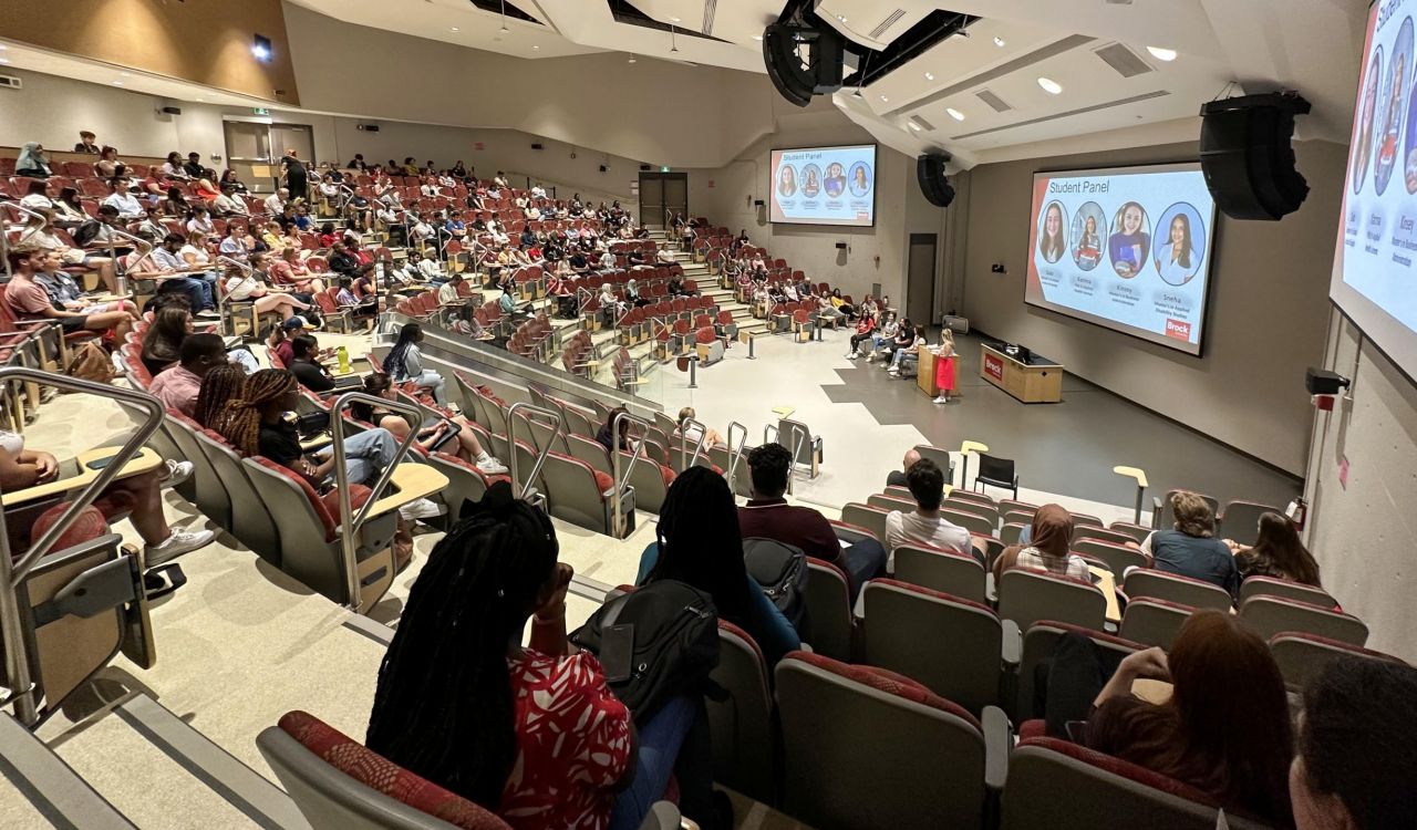 University students sit in a large lecture hall.