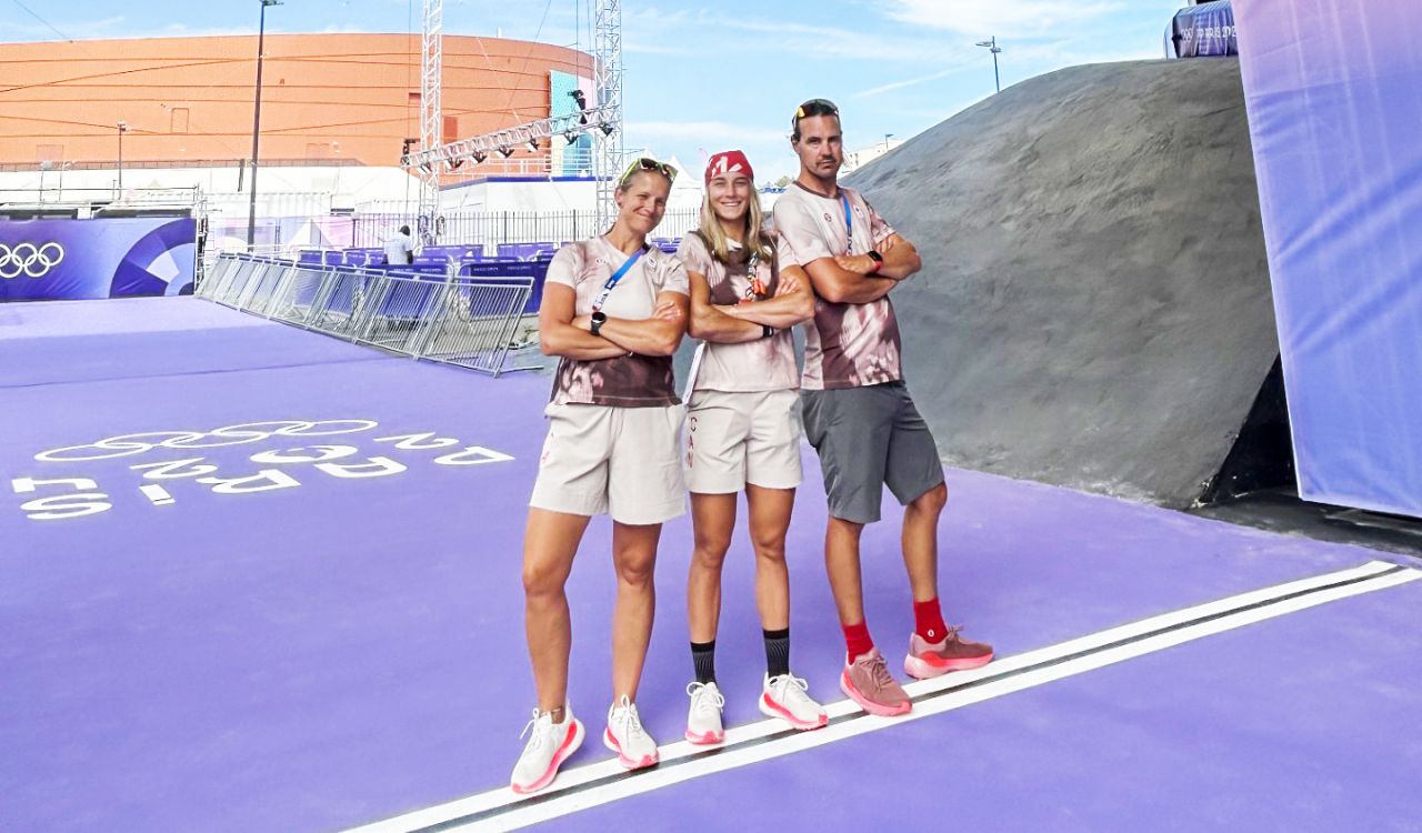 Three people stand near the start line of the BMX cycling track at the 2024 Paris Olympic Games.