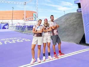 Three people stand near the start line of the BMX cycling track at the 2024 Paris Olympic Games.