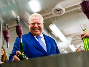 A man fills a wine bottle using a bottling machine.