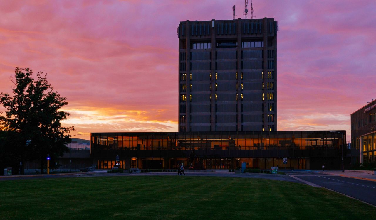 A silhouette of Brock University's Schmon Tower at dusk with a pink and orange sky in the background.