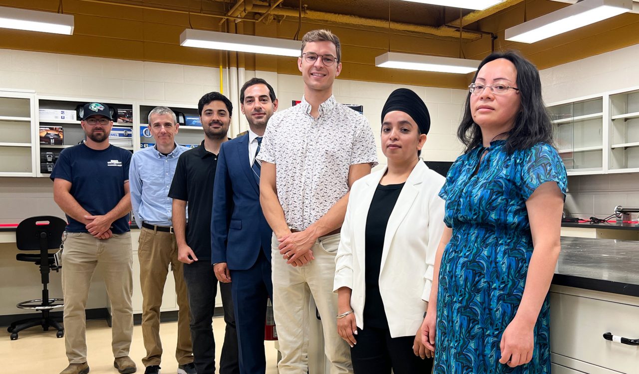 A group of people pose for a photo in a lab room.