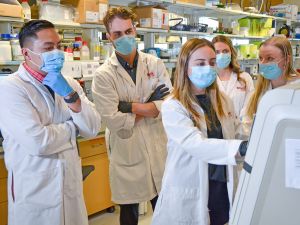 A group of masked researchers stand around a machine in a lab, looking at the screen. From left: Brock University Associate Professor of Kinesiology and Canada Research Chair in Tissue Plasticity and Remodelling Val Fajardo, master’s student Ryan Baranowski, PhD student Jessica Braun, master’s student Briana Hockey and master’s student Emily Copeland.