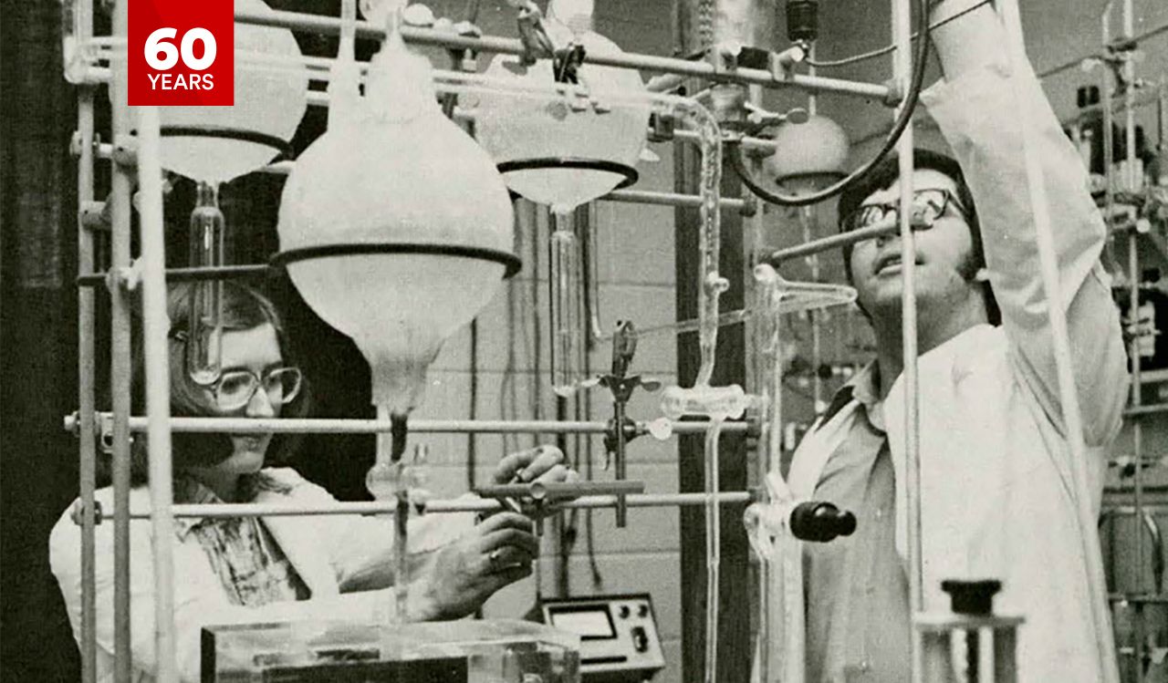 Two scientists, a woman and a man, work in a lab filled with beakers and other equipment.