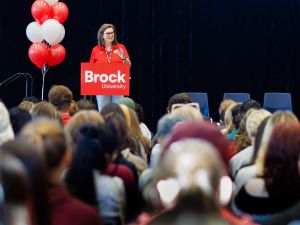 A woman stands at a podium in front of a large crowd.