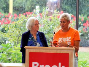 Two women stand at a podium speaking into a microphone.