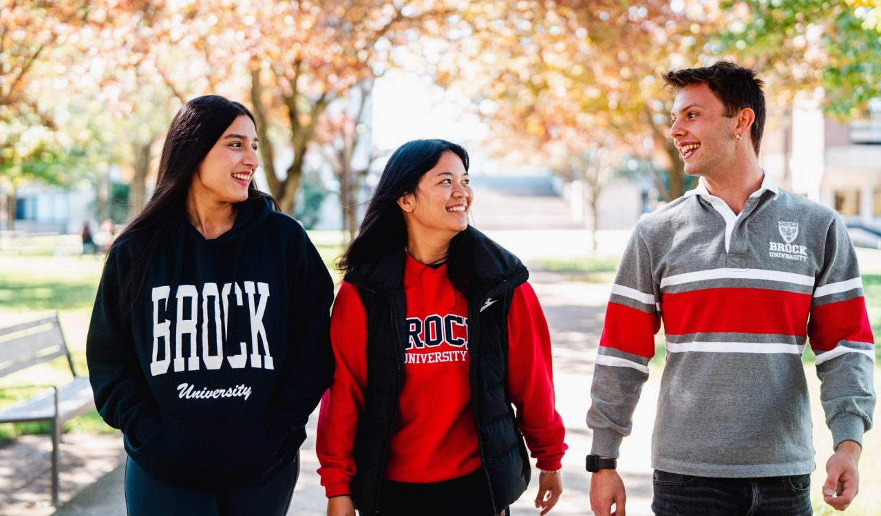 Three university students walk outside in the fall.