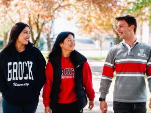 Three university students walk outside in the fall.