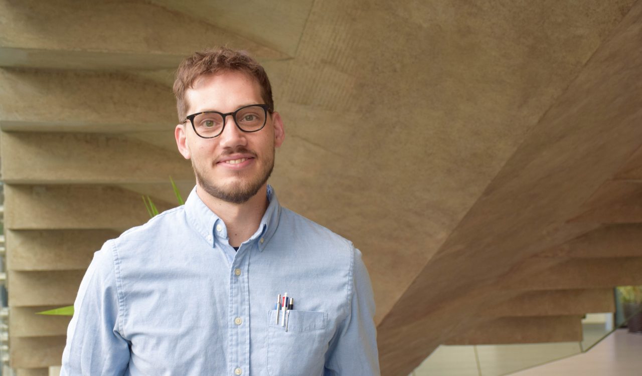 A man poses for a photo in front of concrete stairs.