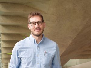 A man poses for a photo in front of concrete stairs.