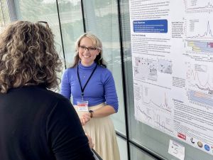 Brock University master’s student Danielle Martin smiles as she speaks with a judge about her research, which is displayed on a large poster behind her entitled, “Estimating atmospheric 14C using tree rings to monitor nuclear generating station emissions and fossil fuel contributions in southern Ontario, Canada.”