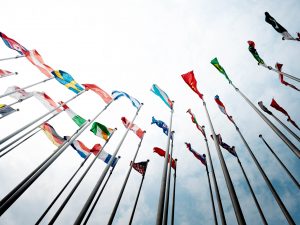 Rows of national flags wave against a blue sky.