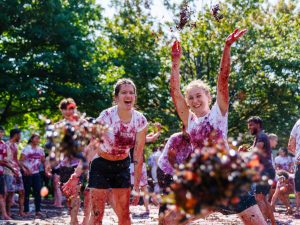 A pair of women throw grapes in the air while laughing outside in Brock University’s Jubilee Court.