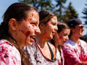 A group of four students, men and women, smile into the sun while covered in grapes.