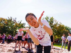 A woman leans into the camera while smiling outdoors, covered in Grapes at Brock University.