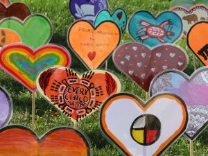 Colourful hearts with messages related to truth and reconciliation are staked into the ground.