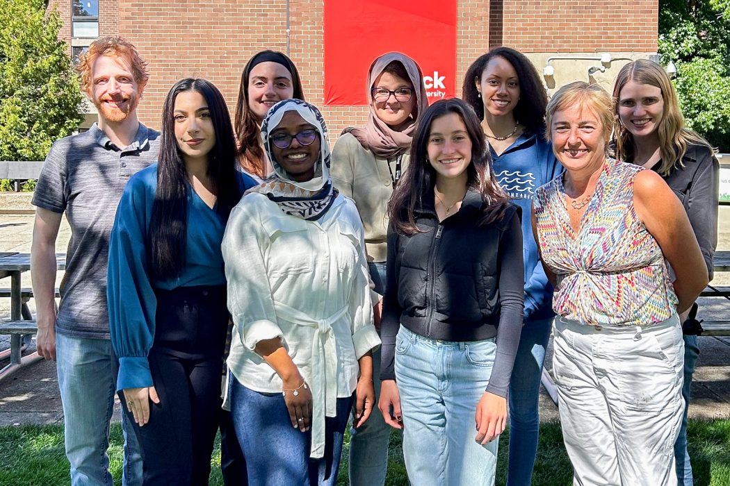 A group photo of nine people outdoors, aligned in two rows.